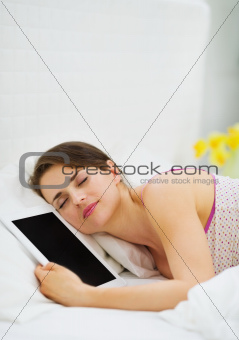 Happy girl sleeping embracing tablet PC