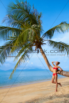 Woman leaning against a palm tree