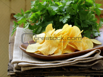 potato chips in wooden plate , on a wooden table