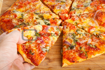 Hand taking homemade pizza