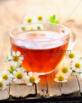 cup of tea and chamomile flowers on a wooden table