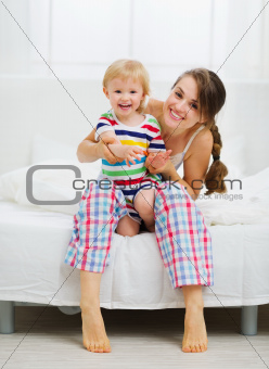 Portrait of smiling mother and baby in bedroom