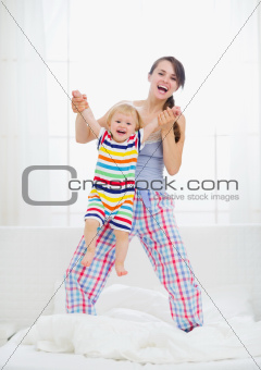 Mom playing with baby in bedroom