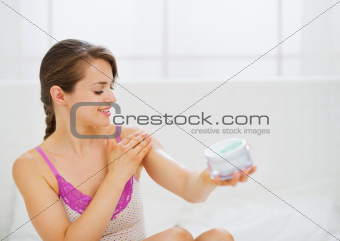 Portrait of self caring woman applying creme on arm