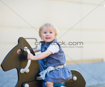 Baby swing on horse on playground. Side view