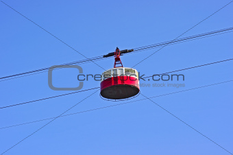 Cable car in mountains on blue sky background