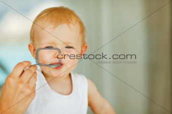Portrait of eat smeared baby feeding by mom