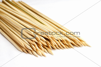 Multiple wooden bamboo skewers laying on white background