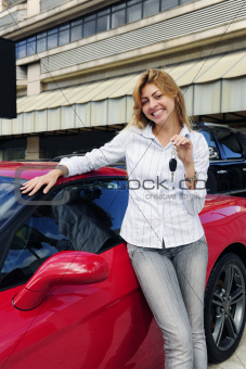 woman showing key of new red sports car