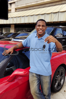 man showing key of new red sports car