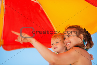 Mother showing something baby on beach