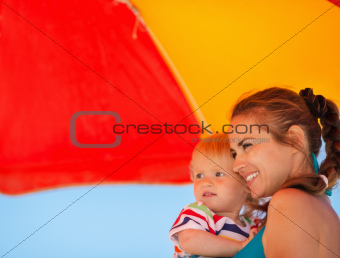 Happy mother and kid looking on copy space on beach
