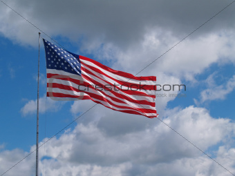American Flag Flying in front of a Blue Cloudy sky