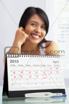 Happy woman with positive pregnancy test and calendar