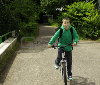 Young school boy with backpack on a bicycle