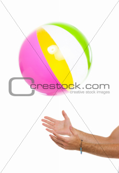 Closeup on males hand throwing beach ball up