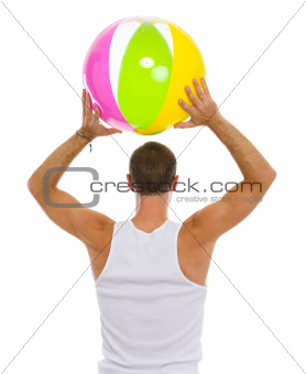Man throwing beach ball. Rear view