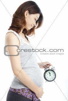 asian Pregnant woman holding alarm clock isolated on white