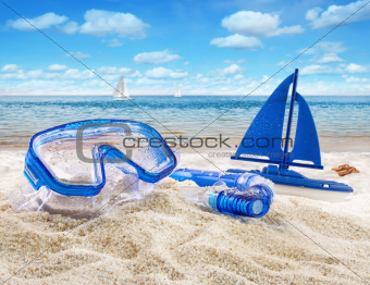 Goggles and toy sailboat in sand 