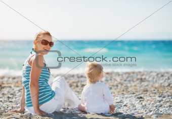 Mother sitting with baby on beach