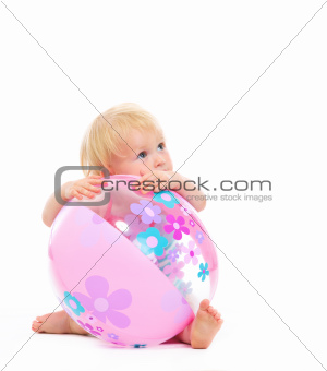 Baby behind beach ball looking on copy space
