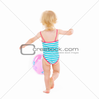 Baby girl in swimsuit playing with ball. Rear view