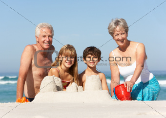 Grandparents And Grandchildren Building Sandcastles Together On Beach Holiday