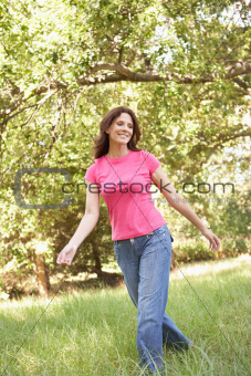 Young Woman Walking Through Long Grass In Park