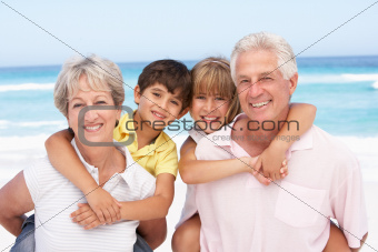 Grandparents And Grandchildren Relaxing On Beach Holiday