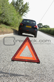 Car Broken Down On Country Road With Hazard Warning Sign In Foreground