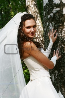The nice young bride is near to a birch