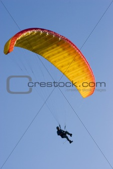 Orange paraglider in a blue sky