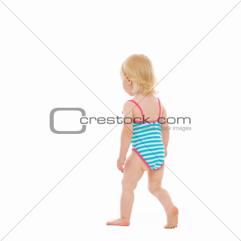 Baby in swimsuit walking away. Rear view
