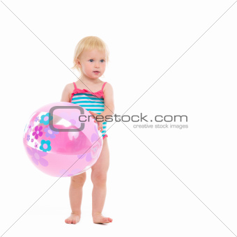 Baby in swimsuit with inflatable beach ball