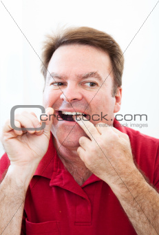 Man Flossing Teeth in the Mirror