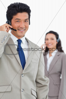 Smiling customer support employee with colleague behind him
