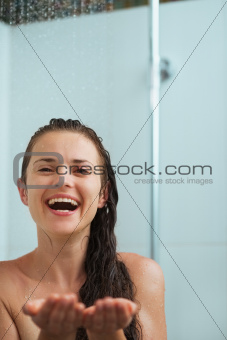 Happy woman catching water drops in shower under water jet