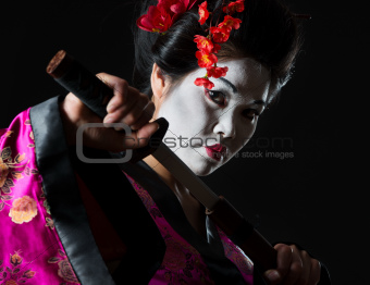 Portrait of geisha pulls out sword of sheath on black