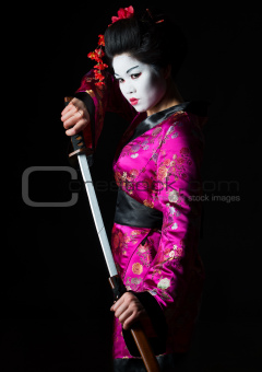 Portrait of geisha warrior pulls out sword of sheath on black