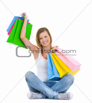 Full length portrait of happy teenage girl sitting with shopping bags