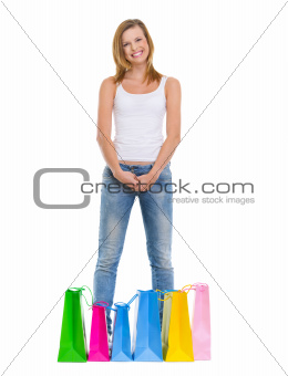 Full length portrait of smiling teenage girl standing among shopping bags