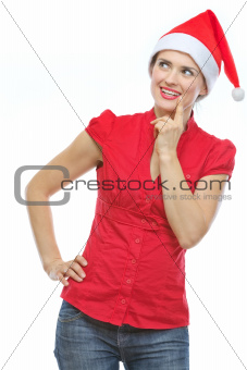 Thoughtful young woman in Christmas hat looking on copy space