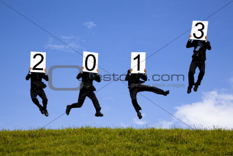 businessman holding 2013  and jumping on the green field