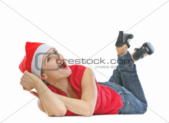 Happy woman in Christmas hat laying on floor and looking on copy space