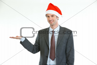 Smiling businessman in Santa's hat presenting something on empty palm