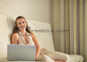 Portrait of happy young woman sitting on couch with laptop