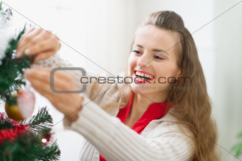 Smiling young woman decorating Christmas tree