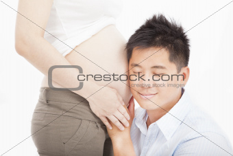 asian father listening to pregnant wife's tummy