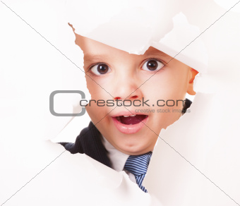 Yawning kid looks through a hole in white paper