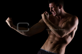 Angry muscular man in attack pose on black